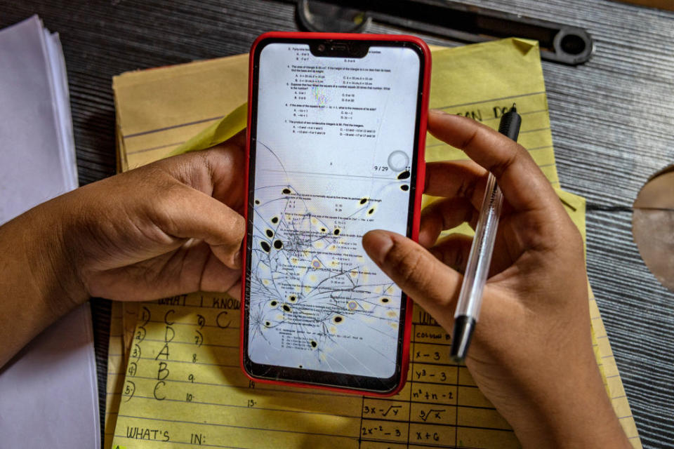 Charilyn Caparas, a grade 8 student, views lessons on her phone with a cracked screen while studying at home as schools remain closed on October 13, 2021 in the coastal village of Pamarawan in Malolos, Bulacan province, Philippines.<span class="copyright">Ezra Acayan/Getty Images</span>