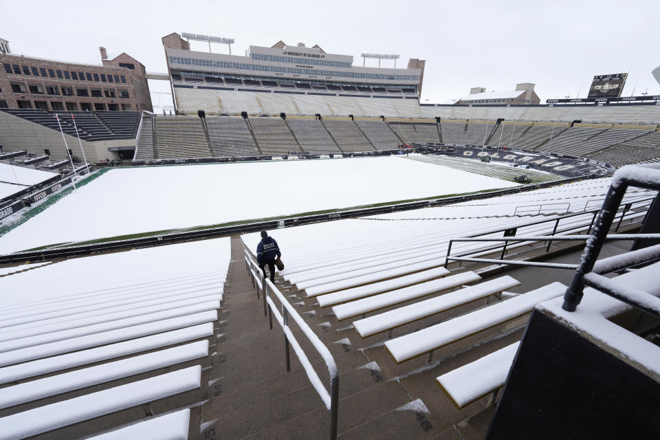 A security guard heads down a set of stairs through the stands as workers clear the gridiron at Folsom Field before Colorado's spring NCAA college football game, Saturday, April 22, 2023, in Boulder, Colo, after a spring snowstorm swept over the intermountain West. (AP Photo/David Zalubowski)