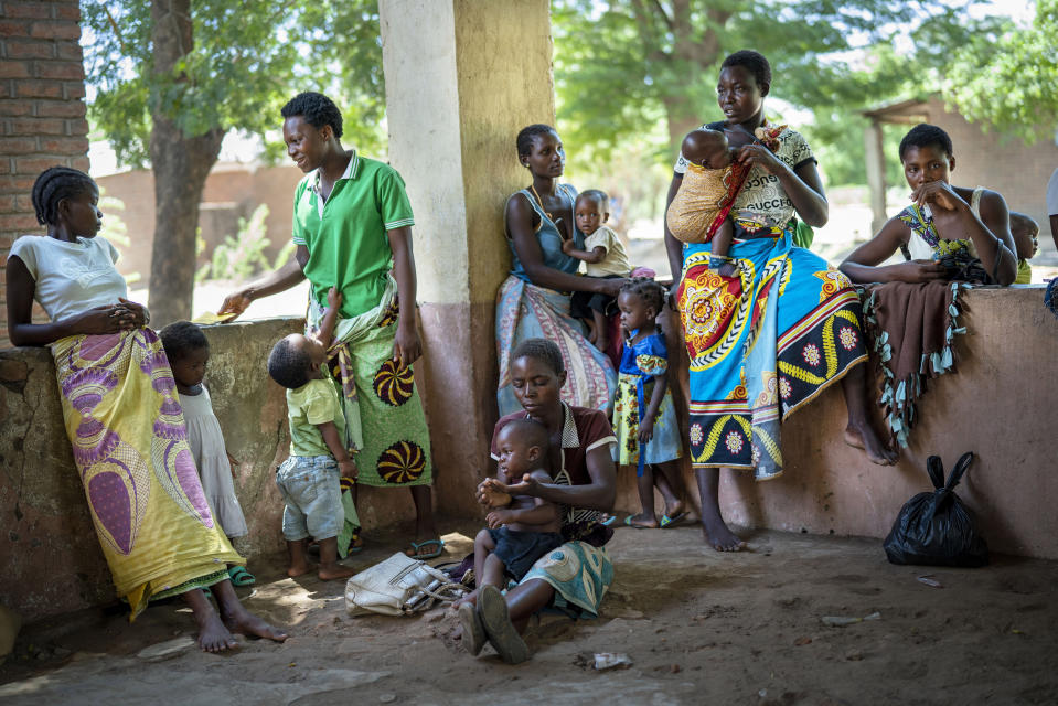 In this photo taken Wednesday Dec. 11, 2019, residents of the Malawi village of Tomali wait to have their young children become test subjects for the world's first vaccine against malaria. Babies in three African nations are getting the first and only vaccine for malaria in a pilot program. World health officials want to see how well the vaccine works in Malawi, Ghana and Kenya before recommending its wider use. (AP Photo/Jerome Delay)