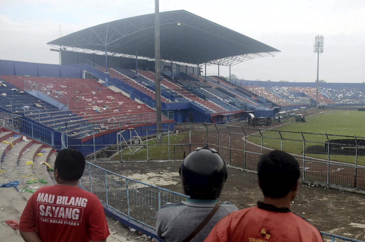 People examine the damage following a soccer match stampede at the Kanjuruhan Stadium in Malang, East Java, Indonesia, Sunday, Oct. 2, 2022. Panic at an Indonesian soccer match after police fired tear gas to to disperse supporters invading the pitch left over 100 people dead, mostly trampled to death, police said Sunday. (AP Photo/Hendra Permana)