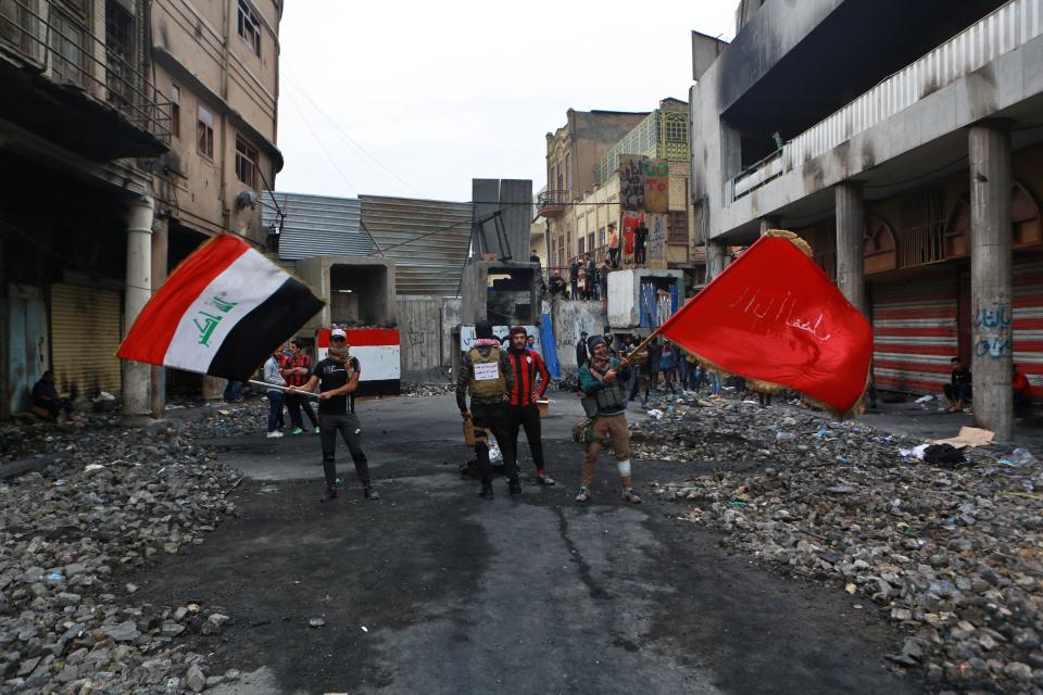 Anti-government protesters gather wave flags on Rasheed Street that is closed by security forces, in Baghdad, Iraq, Sunday, Dec. 1, 2019. Iraq’s parliament approved the resignation of Prime Minister Adel Abdul-Mahdi, amid ongoing violence and anti-government demonstrations. (AP Photo/Khalid Mohammed)