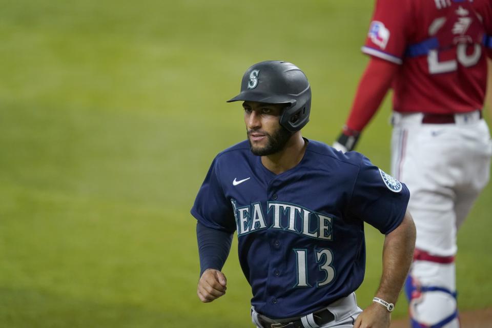 Seattle Mariners' Abraham Toro heads to the dugout after scoring from third on a bases-loaded walk to Dylan Moore during the second inning of the team's baseball game against the Texas Rangers in Arlington, Texas, Friday, July 30, 2021. Rangers catcher Jonah Heim stands near the plate. (AP Photo/Tony Gutierrez)