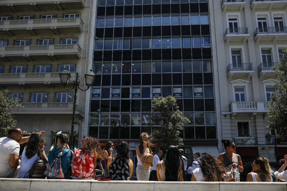 People speak on their phones as they stand outside the building they work in with the Greek Parliament in the background, after a strong earthquake hit near the Greek capital of Athens, Friday, July 19, 2019. The Athens Institute of Geodynamics gave the earthquake a preliminary magnitude of 5.1 but the U.S. Geological Survey gave it a preliminary magnitude of 5.3. The Athens Institute says the quake struck at 2:38 p.m. local time (1113 GMT) about 26 kilometers (13.7 miles) north of Athens. (AP Photo/Petros Giannakouris)