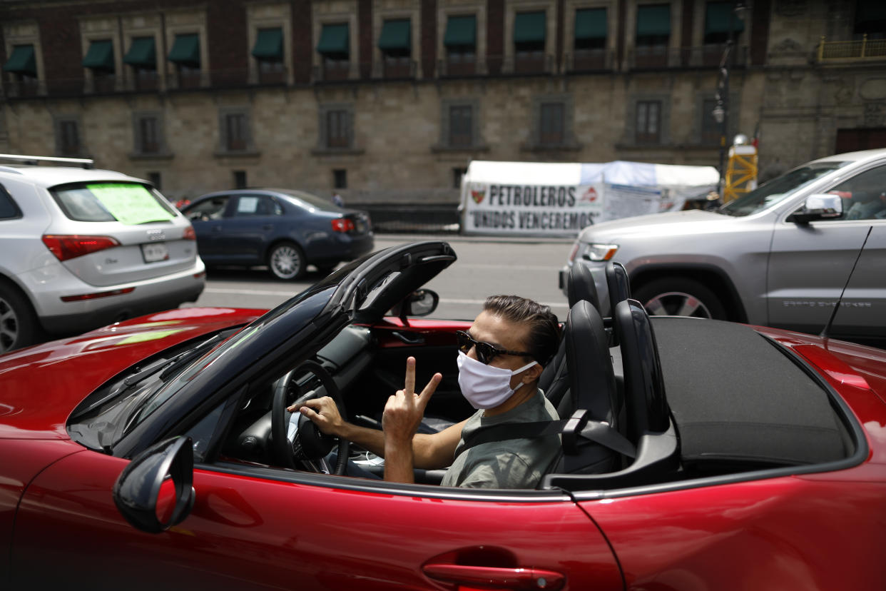 A driver participates in a caravan of cars protest calling for Mexican President Andres Manuel Lopez Obrador to step down, in front of the National Palace in Mexico City, Saturday, May 30, 2020. Hundreds of cars, many adorned with flags and signs criticizing Lopez Obrador, drove in circles past the National Palace on Saturday, honking their horns to protest against the president and his handling of the new coronavirus pandemic. (AP Photo/Rebecca Blackwell)