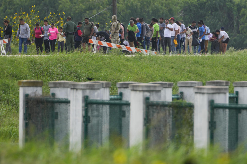 FILE - Migrants talk to officials along a road near the Rio Grande after crossing the Texas-Mexico border, Thursday, May 11, 2023, in Brownsville, Texas. On May 26, The Associated Press reported on stories circulating online incorrectly claiming the U.S. government gives immigrants who cross the country’s border illegally smartphones with unlimited texting and internet access. (AP Photo/Julio Cortez, File)