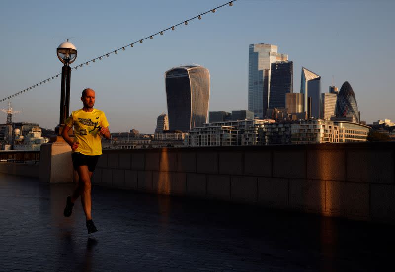 A man runs at sunrise, with the City of London financial district in the background