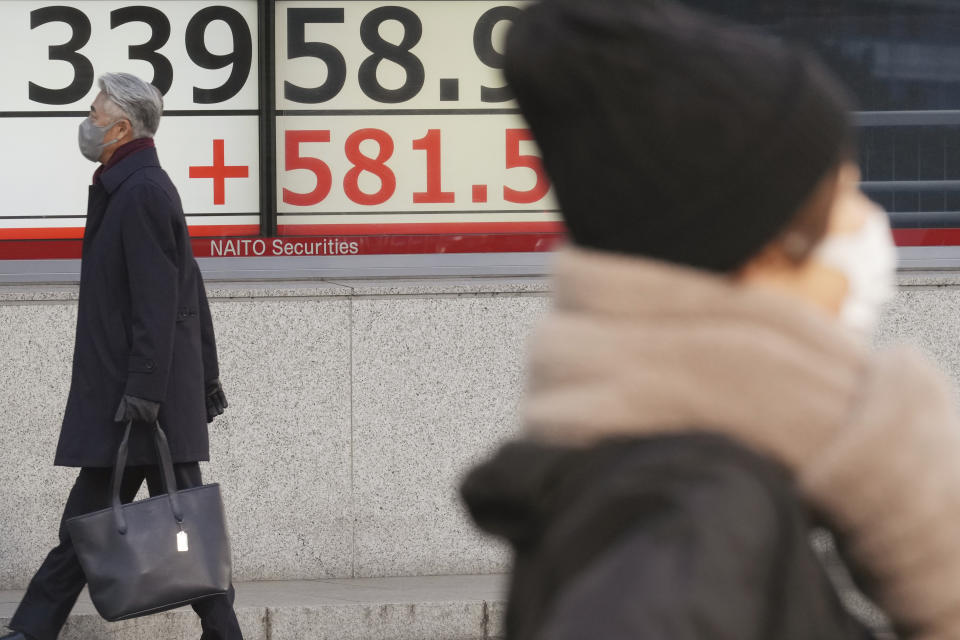 People walk near in front of an electronic stock board showing Japan's Nikkei 225 index at a securities firm Tuesday, Jan. 9, 2024, in Tokyo. (AP Photo/Eugene Hoshiko)