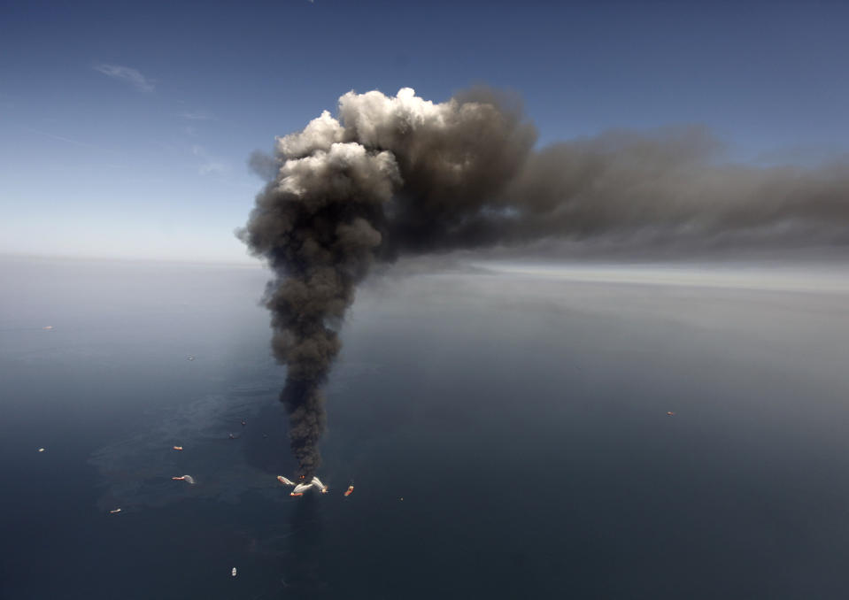 FILE - This Wednesday, April 21, 2010 file photo shows oil in the Gulf of Mexico, more than 50 miles southeast of Venice on Louisiana's tip, as a large plume of smoke rises from fires on BP's Deepwater Horizon offshore oil rig. An April 20, 2010 explosion at the offshore platform killed 11 men, and the subsequent leak released an estimated 172 million gallons of petroleum into the gulf. (AP Photo/Gerald Herbert, File)