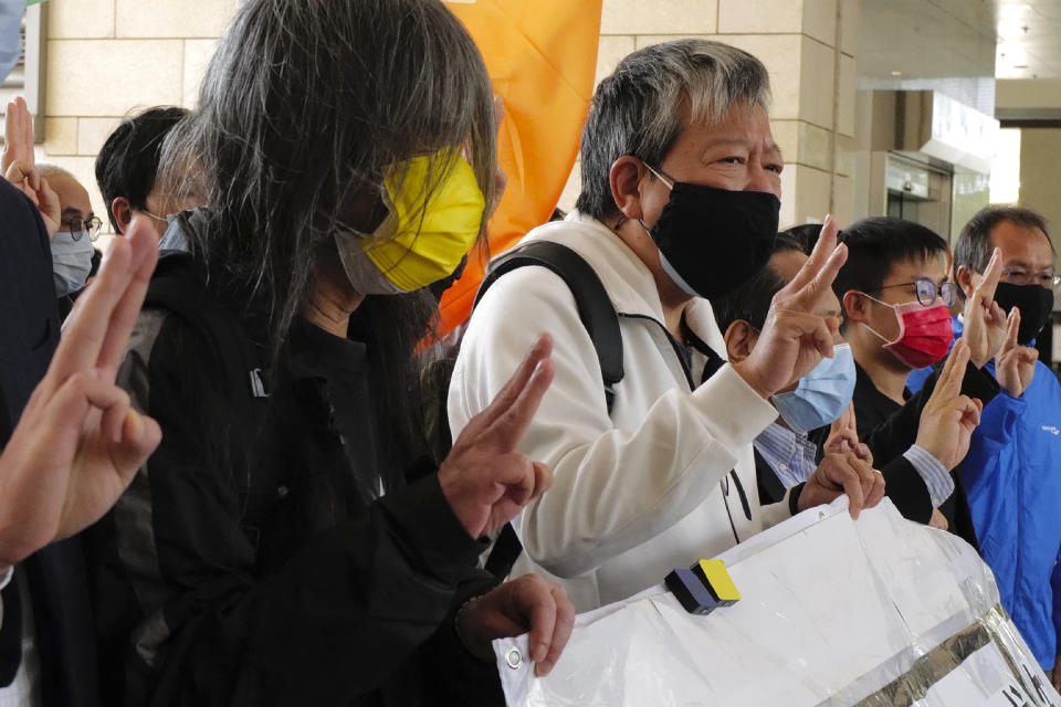 Hong Kong pro-democracy activists Lee Cheuk-yan wearing a black mask and Leung Kwok-hung wearing a yellow mask, shout slogans as they arrive at a court in Hong Kong Tuesday, Feb. 16, 2021. They are among nine prominent Hong Kong's democracy advocates facing trial Tuesday on charges of organizing an unauthorized assembly in August 2019. (AP Photo/Vincent Yu)