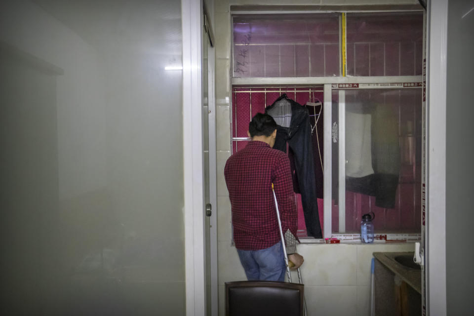 In this Dec. 6, 2019, photo, Wu Yi, who has struggled with Oxycontin abuse, smokes a cigarette while looking out the window of his rented room in Shenzhen in southern China's Guangdong Province. Officially, pain pill abuse is an American problem, not a Chinese one. But people in China have fallen into opioid abuse the same way many Americans did, through a doctor's prescription. And despite China's strict regulations, online trafficking networks, which facilitated the spread of opioids in the U.S., also exist in China. (AP Photo/Mark Schiefelbein)