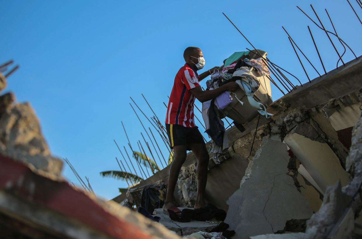 A man recovers belongings from his home that was destroyed by the earthquake in Les Cayes, Haiti, Saturday, Aug. 14, 2021.