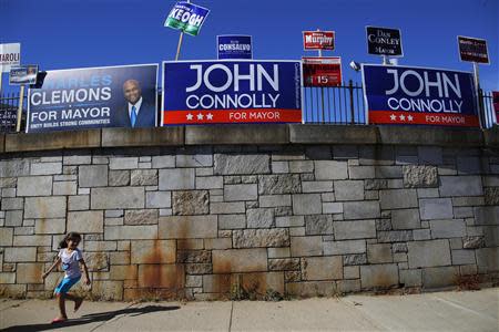 A girl runs under campaign signs outside a polling station in Boston, Massachusetts September 24, 2013. REUTERS/Brian Snyder