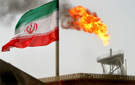 FILE PHOTO: A gas flare on an oil production platform in the Soroush oilfields is seen alongside an Iranian flag in Iran, July 25, 2005. REUTERS/Raheb Homavandi/File Photo