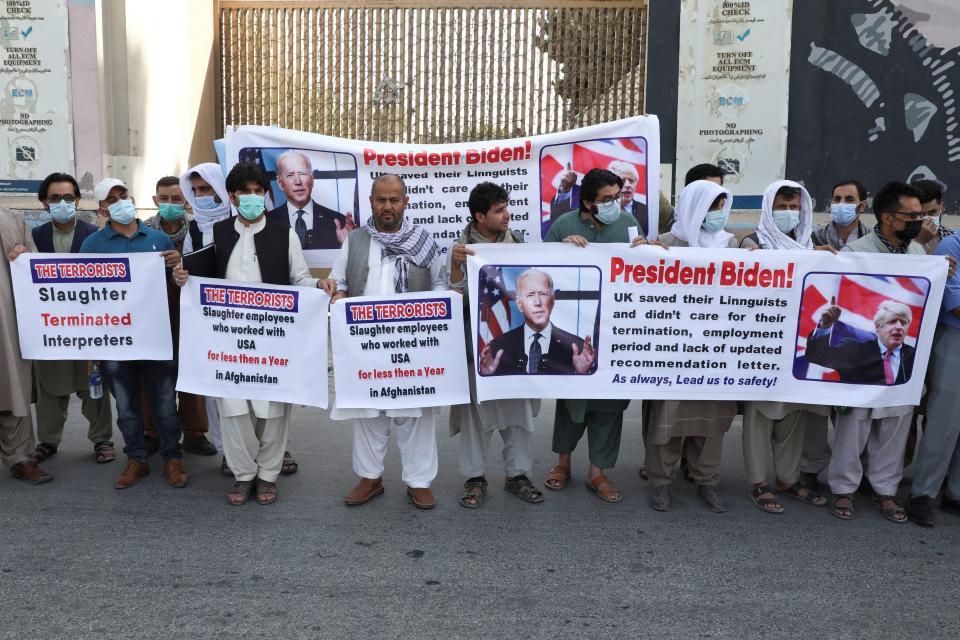 Around 10 men hold signs about the safety of Afghan interpreters in front of the U.S. embassy