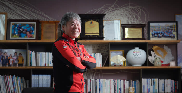 Gil at home, with books and trophies on ledges behind him. 