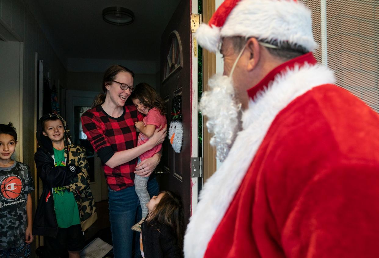 Ray Hillenbrand, 60, of Rochester Hills shows up dressed as Santa to the door of Mandy Gutierrez as she holds her daughter Abigail Gutierrez, 3, while Michael Kenny, 10, left, stands with Shaun-Patrick Kenny, 11, and Amilia Gutierezz, 4, stands at right. Hillenbrand hands out toys to unsuspecting families in Southwest Detroit.