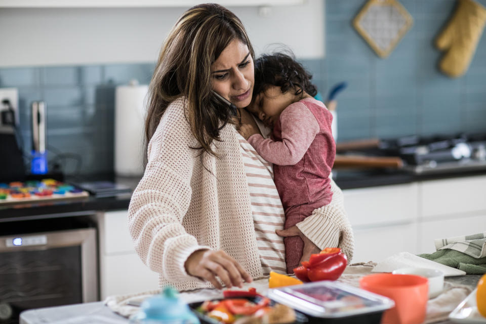 Mother holding baby and multi-tasking in kitchen