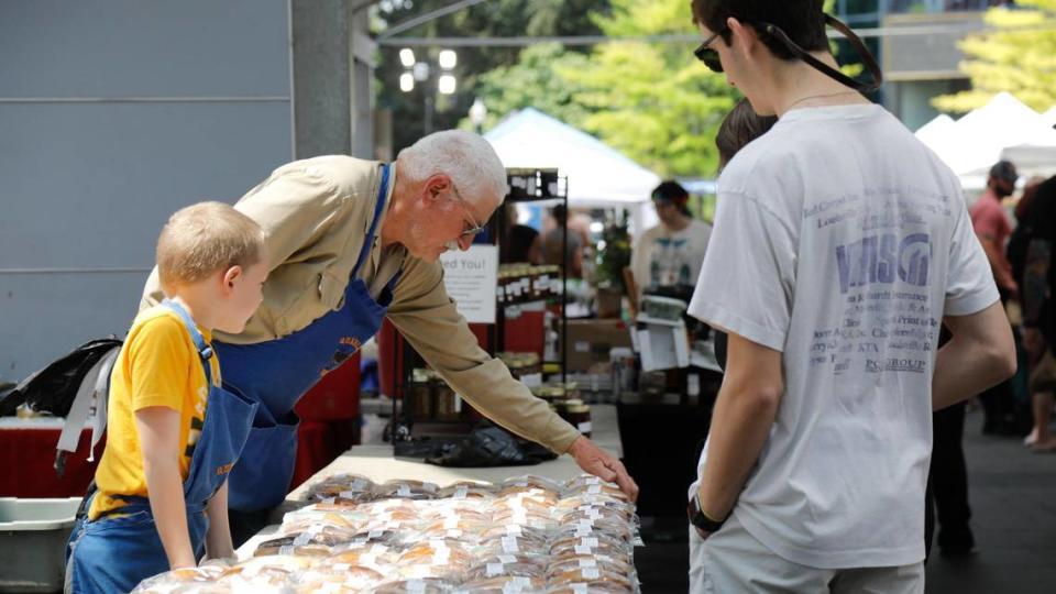 From left, Henry Clary, 8, and his grandfather Paul Quarles sell bread on Saturday, June 24, 2023 at Fifth Third Pavilion in Lexington, Ky. Besides fresh produce and flowers, farmers often sell baked goods.