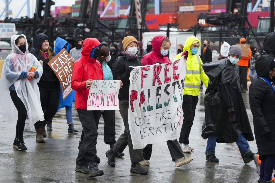 Protesters hold pro-Palestinian signs as they march in a circle while blocking one of the Port of Tacoma entrances to delay the loading of the MV Cape Orlando Monday, Nov. 6, 2023, in Tacoma, Wash. (AP Photo/Lindsey Wasson)
