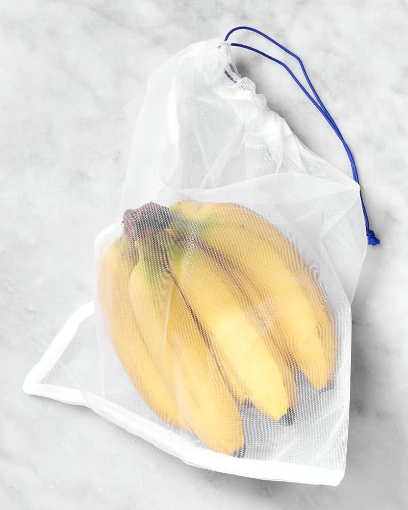shot of bananas in a white mesh produce bag.