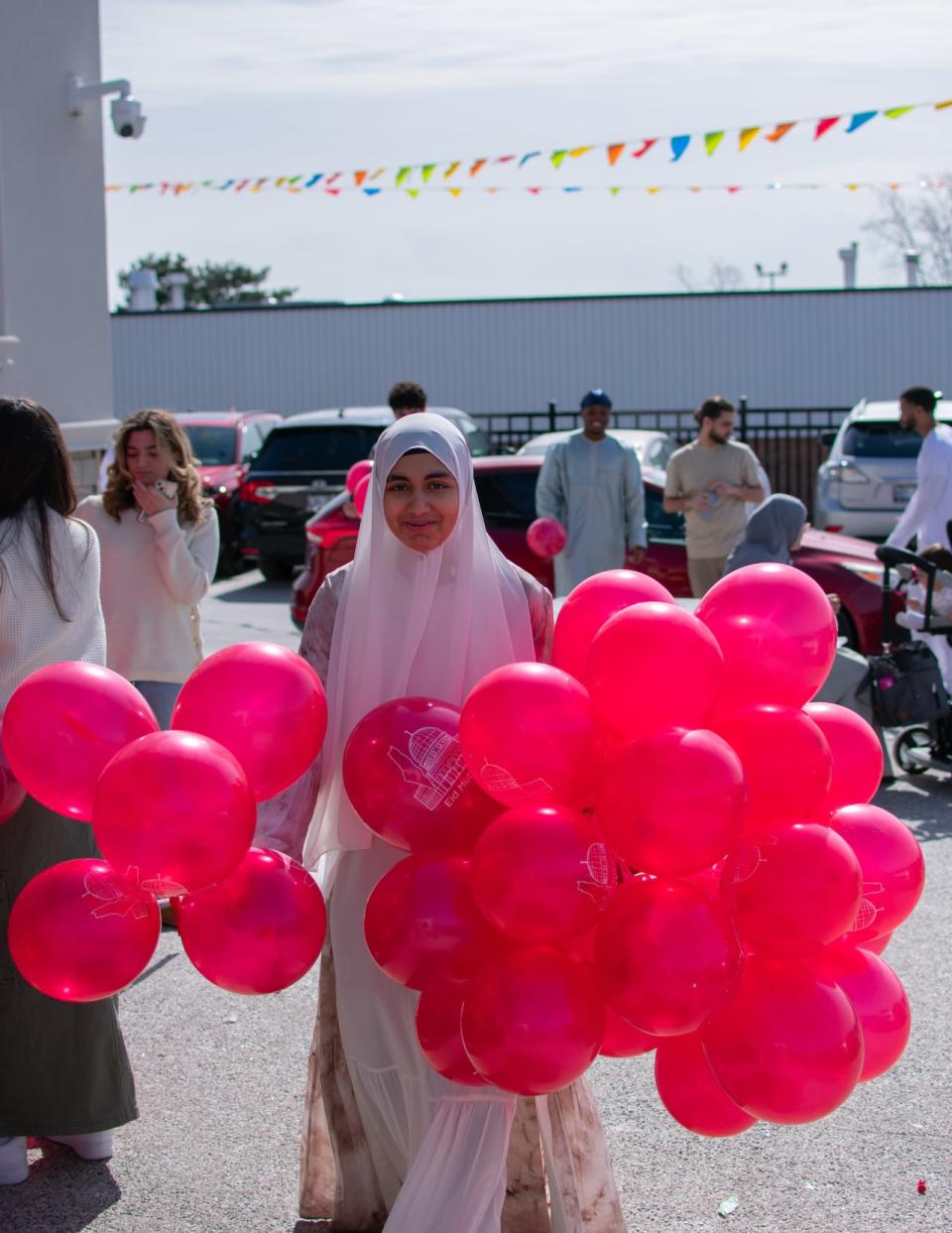 People attend Eid al-Fitr morning prayers at Islamic Community Centre of Ontario in Mississauga, Ont., on April 10, 2024, to mark the end of Ramadan. See woman holding bunches of red balloons in each hand.