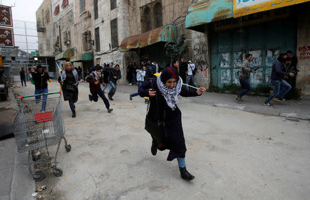 Palestinian demonstrators run for cover during clashes with Israeli troops at a protest against U.S. President Donald Trump's decision to recognise Jerusalem as the capital of Israel, in the West Bank city of Hebron, December 29, 2017. REUTERS/Mussa Qawasma