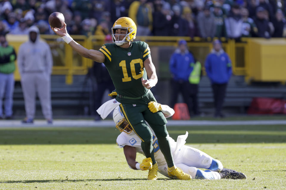 Green Bay Packers quarterback Jordan Love (10) attempts a pass as Los Angeles Chargers linebacker Eric Kendricks tries to bring him down during the first half of an NFL football game, Sunday, Nov. 19, 2023, in Green Bay, Wis.(AP Photo/Mike Roemer)