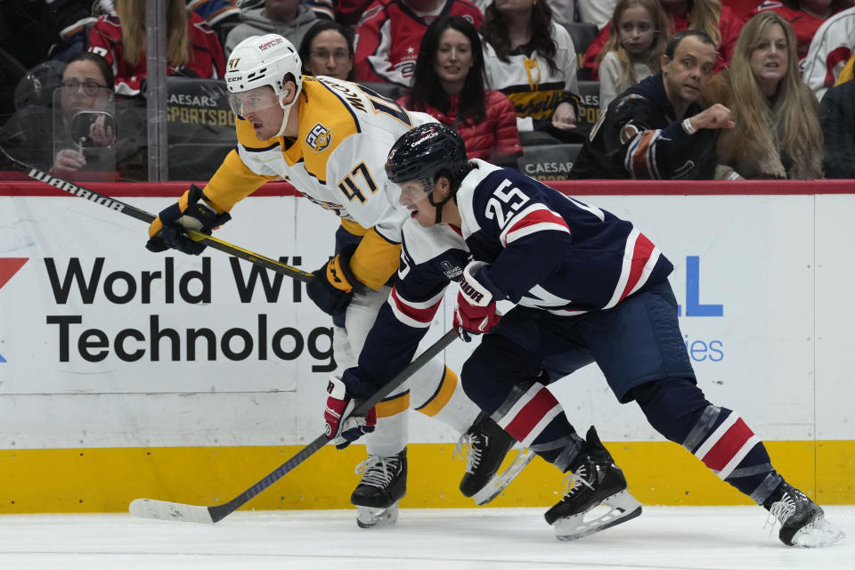 Nashville Predators right wing Michael McCarron (47) and Washington Capitals defenseman Ethan Bear (25) battle along the boards during the first period of an NHL hockey game in Washington, Saturday, Dec. 30, 2023. It is Bear's first game as a Capital. (AP Photo/Susan Walsh)
