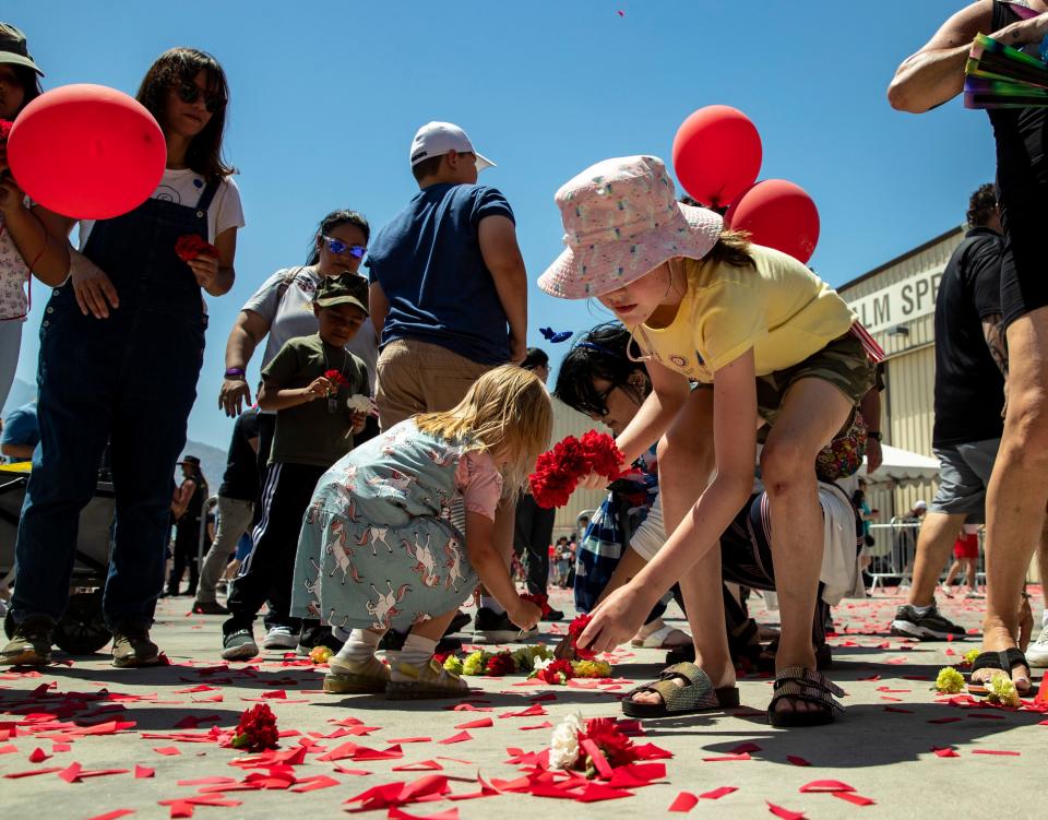 9-year-old Harlee Hallacy-Brown of Cathedral City picks up flowers during the Memorial Day Air Fair & Flower Drop at the Palm Springs Air Museum in Palm Springs, Calif., Monday, May 29, 2023. 