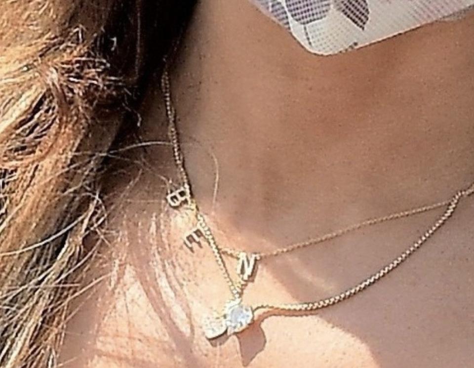 A zoom in on Jen's jewelry where a gold necklace that says BEN can be seen