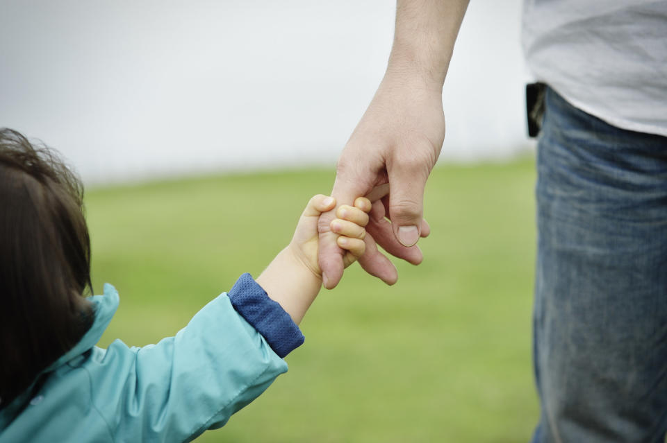 close up of a child's hand wrapped around an adult's finger