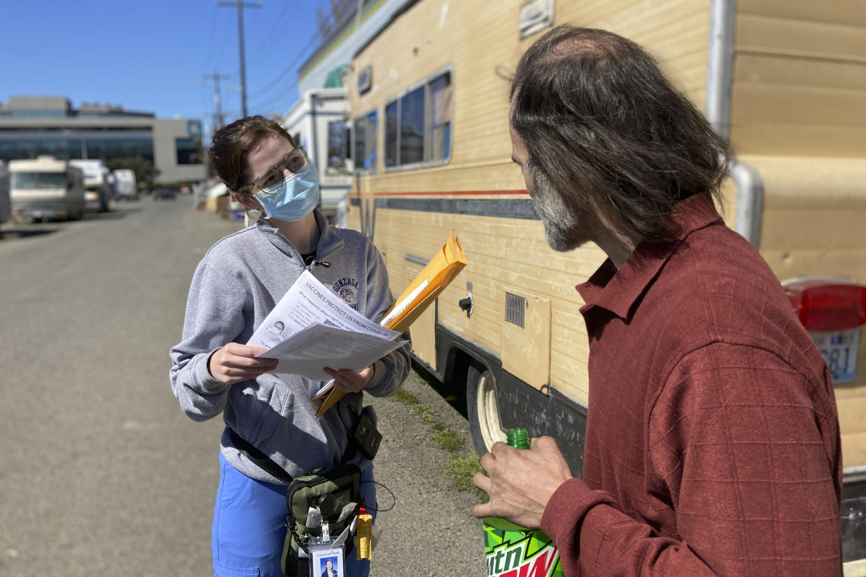 Moira Andrews, a street outreach nurse for Neighborcare Health, speaks with Shane Pisson, 48, who lives in an encampment in the Georgetown neighborhood of Seattle on Monday, April 12, 2021. Andrews spoke with Pisson about the COVID-19 vaccines and answered questions in an effort to vaccinate people experiencing homelessness. Advocates say homeless people are at greater risk of being infected and greater risk of hospitalization and death than the average person, and they should have been prioritized earlier. (AP Photo/Manuel Valdes)