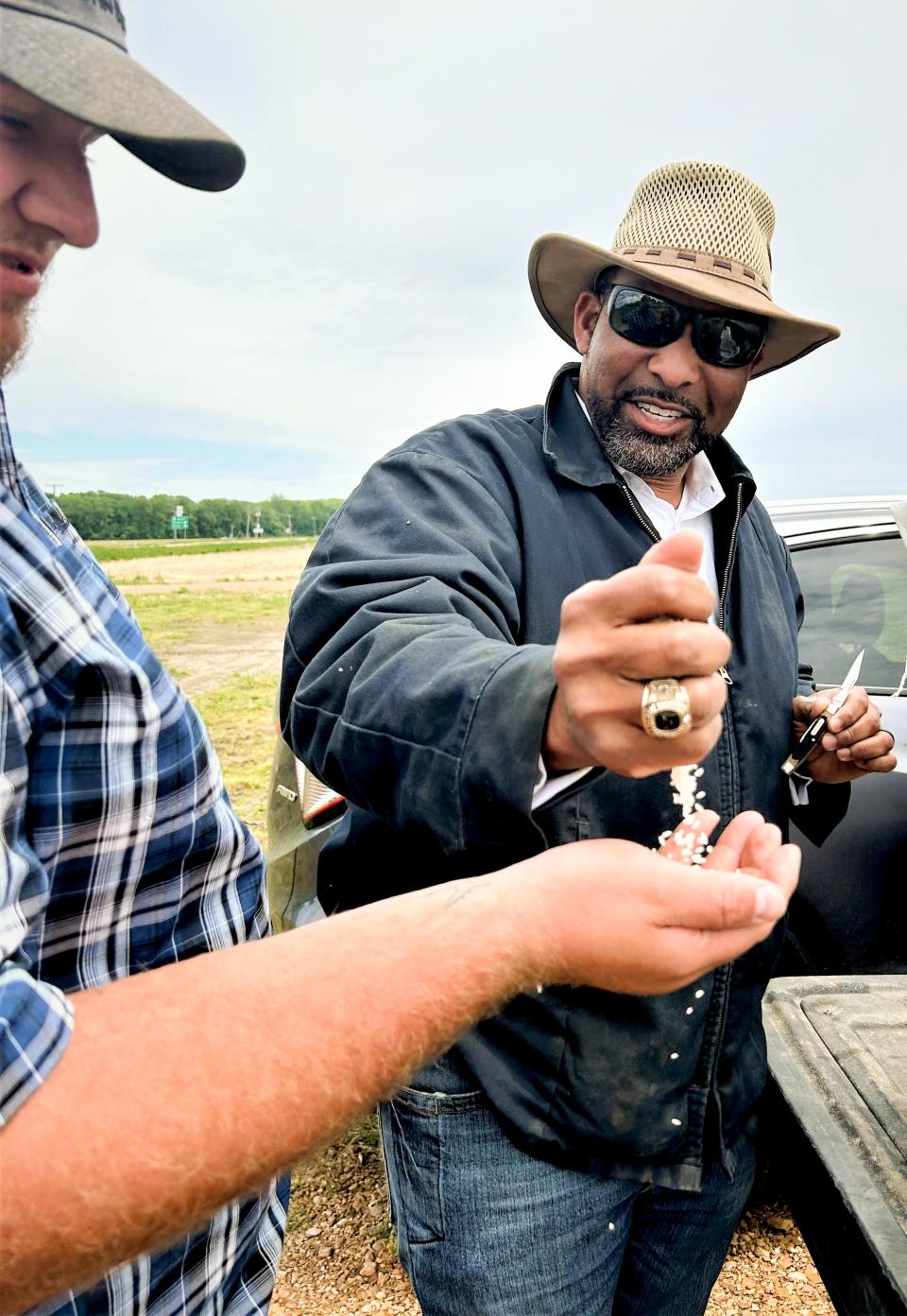 PJ Haynie shows off some of his rice to a worker on the farm.