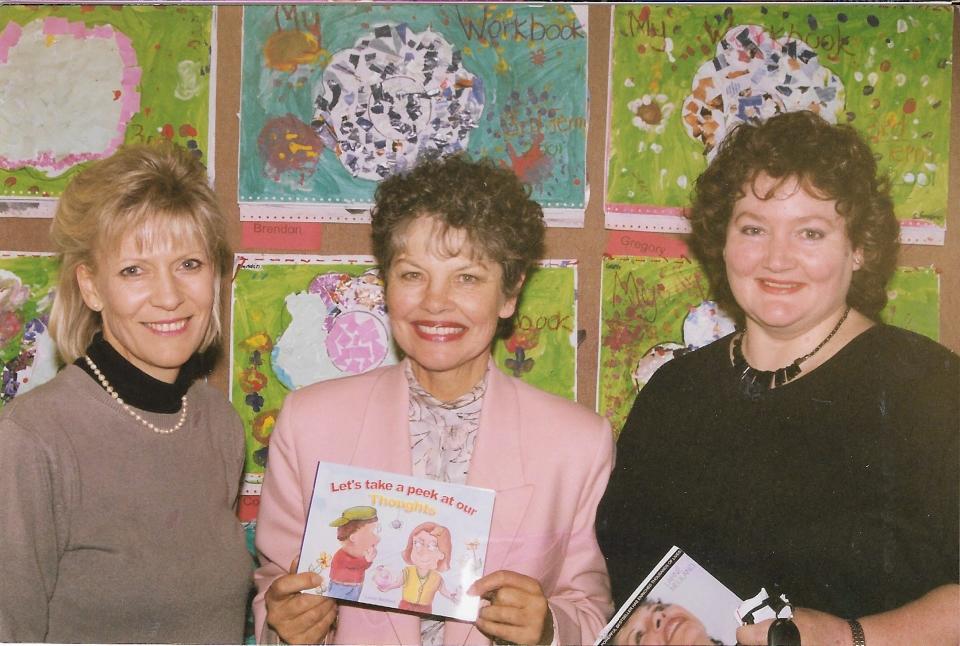 Author Larne Neuland shows offer her children's book, "Let's take a Peek at our Thoughts," at a school in South Africa.