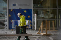 A construction worker stands in front of a door with the EU stars at EU headquarters in Brussels, Wednesday, Oct. 9, 2019. Irish Prime Minister Leo Varadkar said that big gaps remain between Britain and the European Union as they try to secure a Brexit deal by next week.(AP Photo/Virginia Mayo)