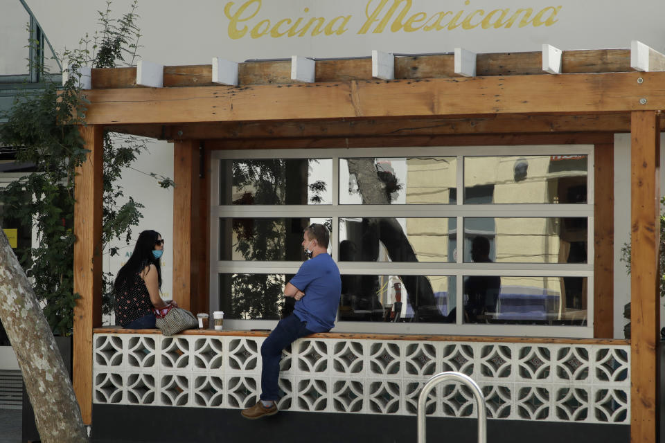 A couple drink beverages outside of Olla Mexican restaurant on Monday, July 6, 2020, in San Jose, Calif. The Independence Day weekend saw one of Santa Clara County's largest increases in COVID-19 cases to date, which came as the state of California denied the county's application for further reopening of businesses and activities. (AP Photo/Ben Margot)