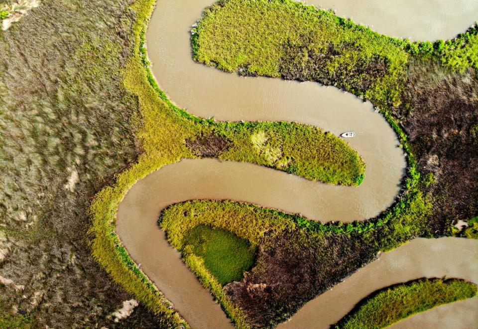 A crabber checks his traps along an estuary of Hancock County marsh near Bayou Caddy on Monday July 26, 2021.