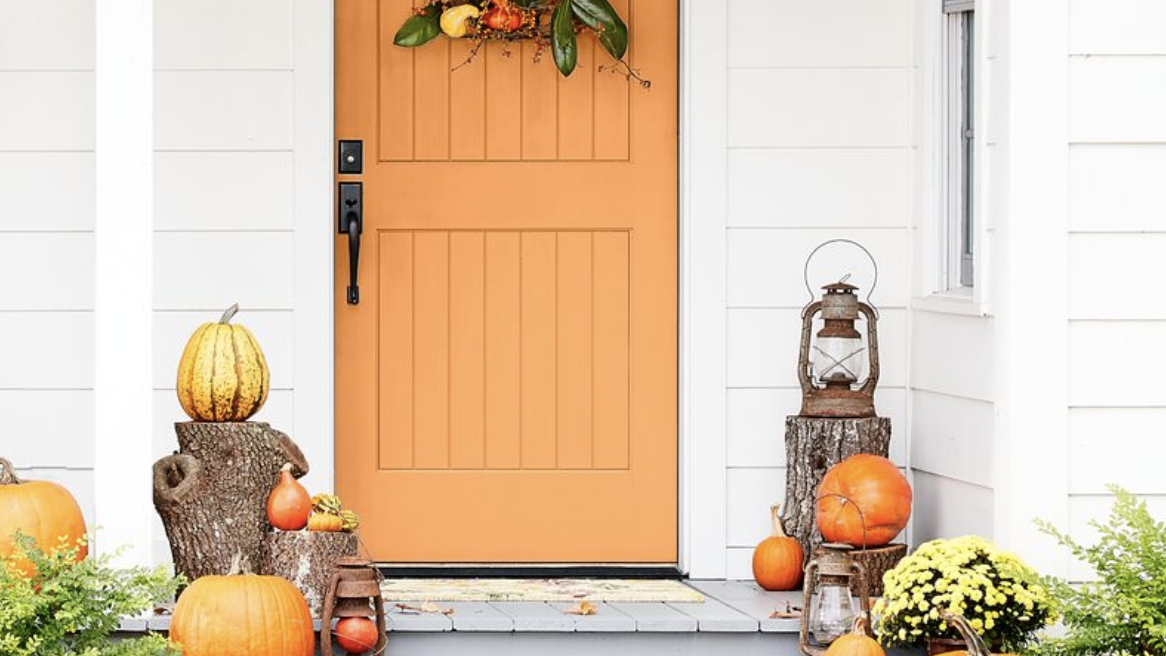 fall porch with orange door and dog in the yard