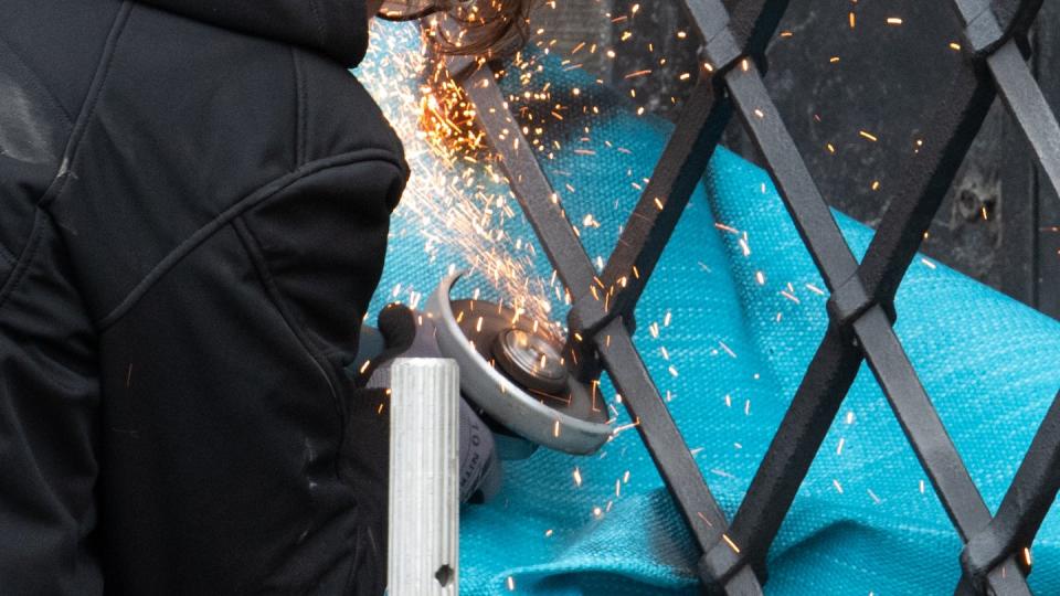 Mitarbeiter einer Restaurierungsfirma arbeiten mit einem Winkelschleifer am durchtrennten Gitterfenster des Grünen Gewölbes.