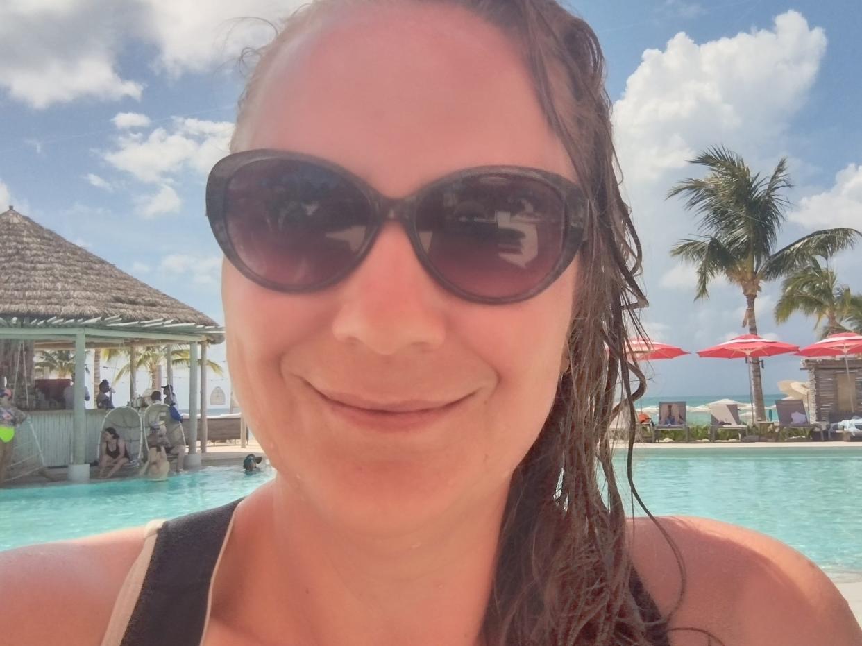 Woman wearing black sunglasses smiling for a selfie in a pool