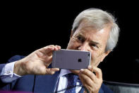 Vincent Bollore, Chairman of the Supervisory Board of media group Vivendi, takes pictures with his mobile phone while attending the company's shareholders meeting in Paris, France, April 19, 2018. REUTERS/Charles Platiau