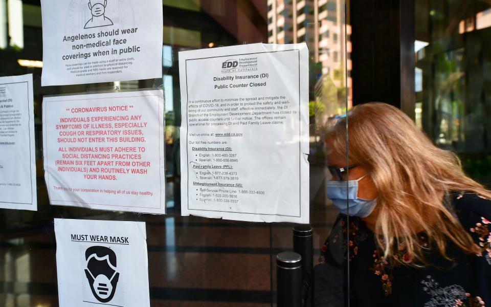 A woman wearing a facemask enters a building where the Employment Development Department has its offices in Los Angeles, California on May 4, 2020, past a posted sign mentioning the closure of the offices's public access counters due to the coronavirus pandemic. - Dismal US employment figures are expected with the release Friday May 8 of figures for April's US jobs report, with 30 million Americans filing for unemployment in the last six weeks. (Photo by Frederic J. BROWN / AFP) (Photo by FREDERIC J. BROWN/AFP via Getty Images)