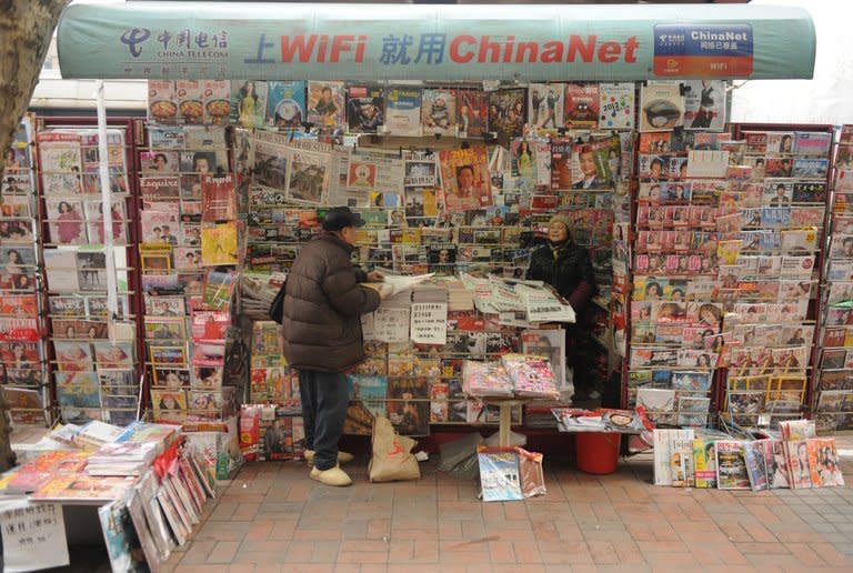 A newspaper vendor (R) talks to a customer at her booth on a street in Shanghai on January 8, 2013. Protesters have mounted a second day of rallies calling for press freedom in China, as social media users and celebrities backed a campaign which poses a test for the nation's new leaders