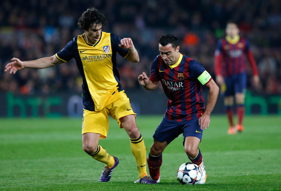 Barcelona's Xavi Hernandez, right, fights for the ball with Atletico's Tiago during a first leg quarterfinal Champions League soccer match between Barcelona and Atletico Madrid at the Camp Nou stadium in Barcelona, Spain, Tuesday April 1, 2014. (AP Photo/Emilio Morenatti)