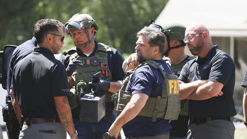 Law enforcement agents confer at the home of Craig Deeleuw Robertson who was shot and killed by FBI agents in Provo on Wednesday, Aug. 9, 2023. Robertson posted threatening comments about President Joe Biden hours before the president was scheduled to visit Utah.