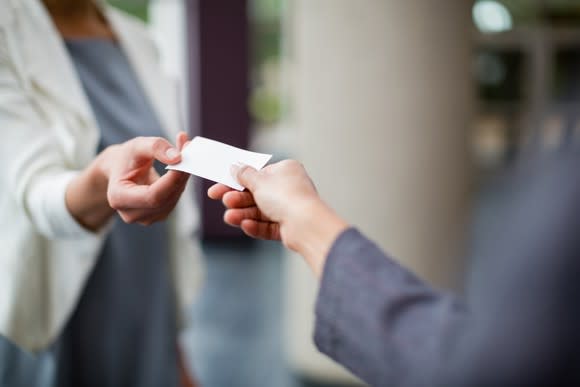 Woman giving another her business card.