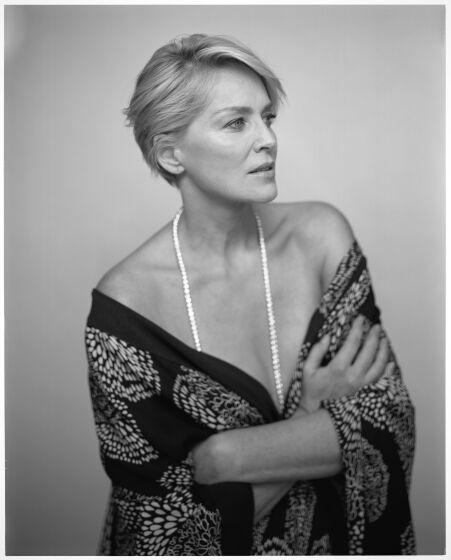 A large-format, black-and-white photo of actor Sharon Stone, waist up, looking pensive.