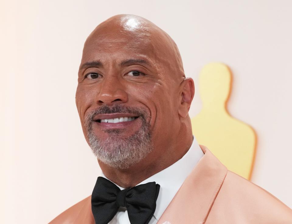 Dwayne Johnson wears a bow tie and cream colored suit