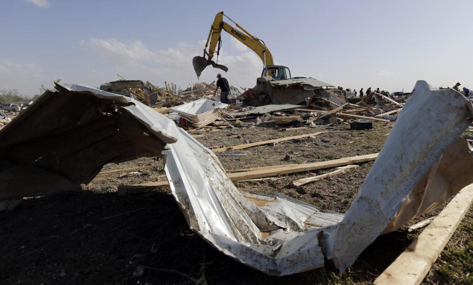 Drew Thomas looks through debris at the home of Ryan Henry after it was destroyed by a tornado, Monday, April 28, 2014, in Vilonia, Ark. A dangerous storm system that spawned a chain of deadly tornadoes killed dozens from the Midwest to the Deep South. (AP Photo/Eric Gay)