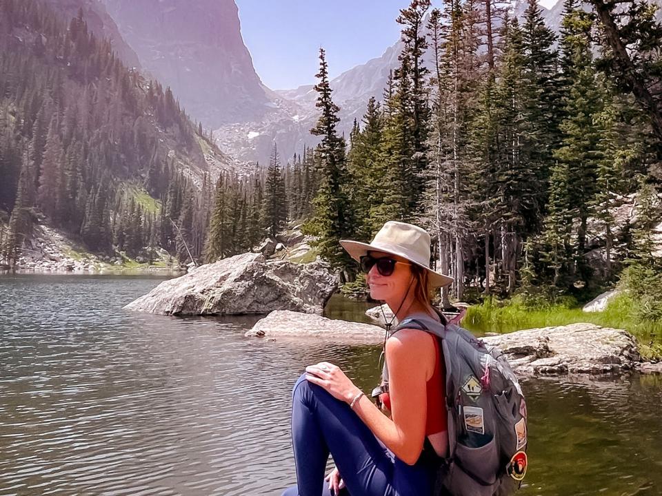 Emily sitting on a rock by a lake at Rocky Mountain National Park.